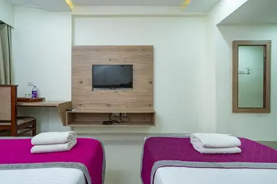 a room with two beds and a tv on a wall at Nexstay Crystal Residency in Kozhikode