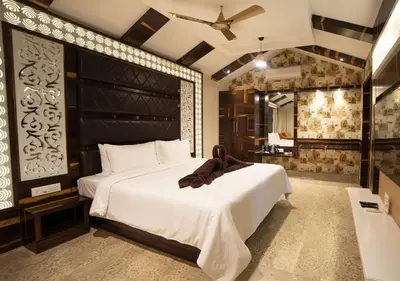 a bedroom with a large white bed with a black headboard at SR Jungle Resort in Coimbatore