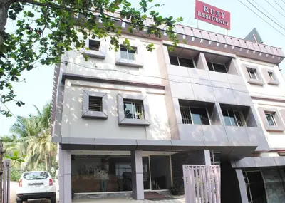 a white building with a car parked in front of it at Ruby Residency in Kozhikode