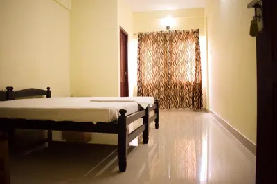 a bedroom with two beds and a window at Ruby Residency in Kozhikode