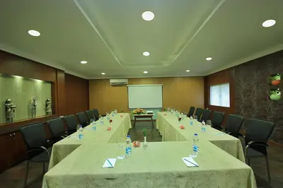 a conference room with long tables and chairs and a screen at Silent Shores Resort & Spa in Mysore