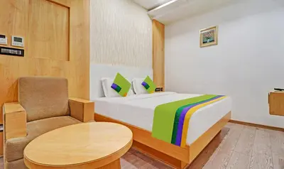 a bedroom with a bed and a chair and a table at Treebo Vinayak Inn, 600 Mts From Coimbatore Railway Station in Coimbatore
