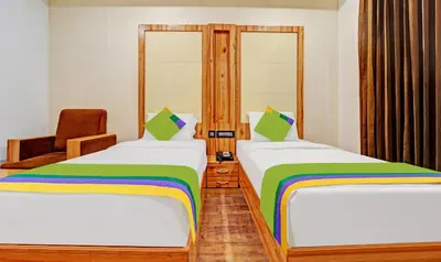 a room with two beds and a chair at Treebo Vinayak Inn, 600 Mts From Coimbatore Railway Station in Coimbatore