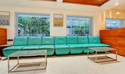 a living room with a blue couch and two windows at Treebo Vinayak Inn, 600 Mts From Coimbatore Railway Station in Coimbatore