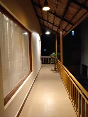 a balcony of a house at night with a window at Olives Pleasant Stays in Ooty