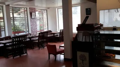 a dining room with tables and chairs and windows at Olives Pleasant Stays in Ooty