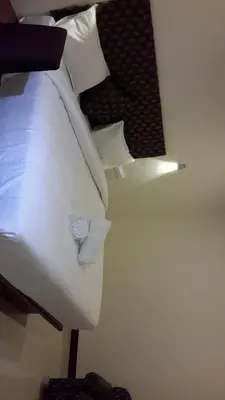 a close up of a bed with white pillows at Olives Pleasant Stays in Ooty