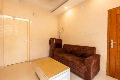 a living room with a couch and a refrigerator at Daan Ambalath Maple Leaves in Guruvāyūr