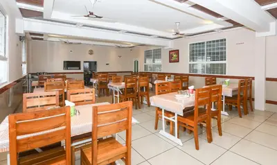an empty restaurant with wooden tables and chairs at Treebo Durga Boji Grand, Gonikoppal Town in Gonikoppal