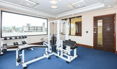 a gym with cardio equipment and a large window at Treebo Durga Boji Grand, Gonikoppal Town in Gonikoppal