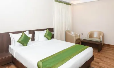 a hotel room with a bed and a chair at Treebo Durga Boji Grand, Gonikoppal Town in Gonikoppal
