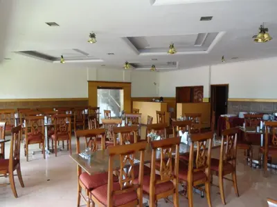 a dining room filled with wooden tables and chairs at Hotel Lakeview in Ooty