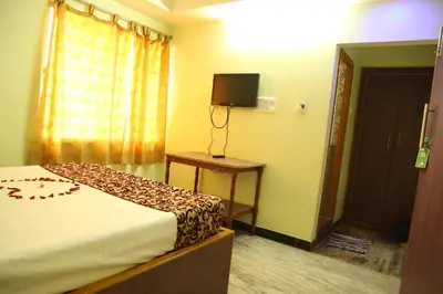 a bedroom with a bed and a television on a table at Hotel Vijay in Pollāchi