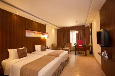 a hotel room with two beds and a television at Gokulam Park Coimbatore in Coimbatore