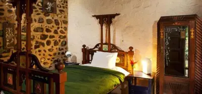 a bedroom with a bed with a green bedspread at Elephant Valley Eco Farm Hotel in Kodaikānāl