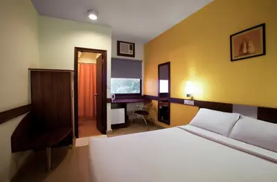 a bedroom with a bed and a desk and a chair at Ginger Tirupur in Tiruppūr