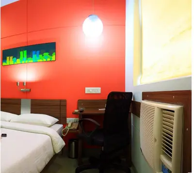 a room with two beds and a desk with a chair at Ginger Tirupur in Tiruppūr