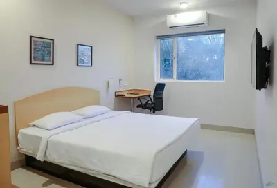 a bedroom with a bed and a desk and a window at Ginger Tirupur in Tiruppūr