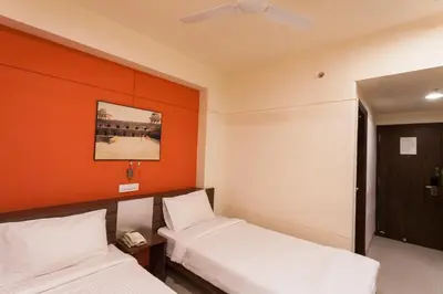two beds in a room with an orange wall at Ginger Tirupur in Tiruppūr