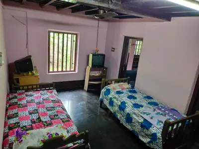 a room with two beds and a tv in it at Meadows in Trichūr