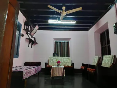 a living room with a ceiling fan and a table and chairs at Meadows in Trichūr
