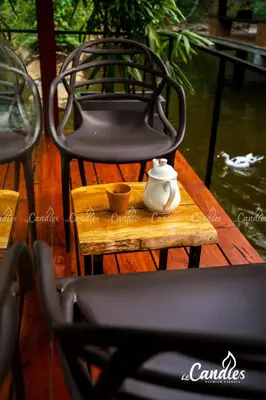 a tea pot sitting on a wooden table next to a chair at Le Candles Resort in Kozhikode