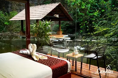 a room with a bed and chairs on a deck at Le Candles Resort in Kozhikode