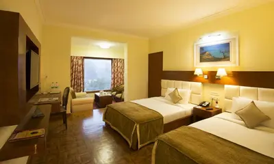 a hotel room with two beds and a living room at Gem Park Ooty in Ooty