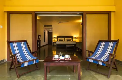 a room with two chairs and a table and a bed at Amritara Ambatty Greens Resort in Virajpet