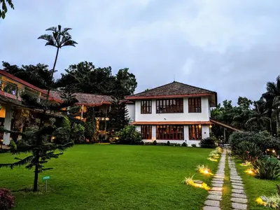 a house with a lawn in front of it at Amritara Ambatty Greens Resort in Virajpet