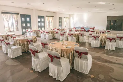 a banquet hall with tables and chairs with bows at Amritara Ambatty Greens Resort in Virajpet