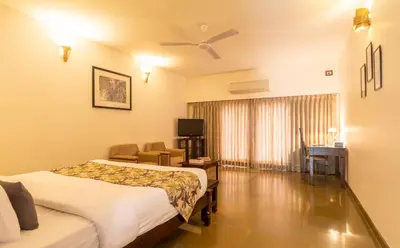 a hotel room with two beds and a television at Amritara Ambatty Greens Resort in Virajpet
