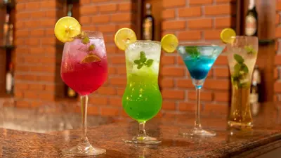 four different colored cocktails sitting on a bar at Amritara Ambatty Greens Resort in Virajpet