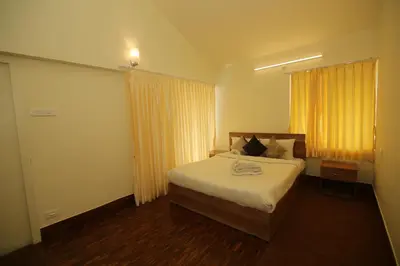 a bedroom with a bed and a window with yellow curtains at Tiger Hill Homestay in Ooty