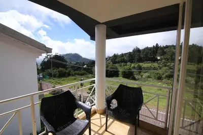 two chairs sitting on a balcony with a view at Tiger Hill Homestay in Ooty