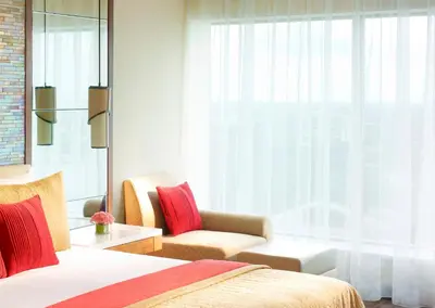a bedroom with a bed and a chair and a window at Vivanta Coimbatore in Coimbatore