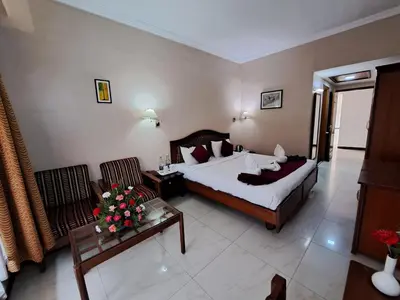 a hotel room with a bed and a living room at Hotel Preethi Classic Towers in Ooty