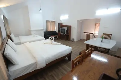 a hotel room with a bed and a table and a desk at Delightz Inn in Ooty