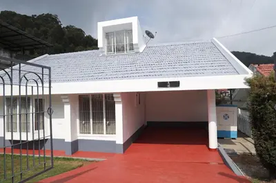 a small white house with a red driveway at Delightz Inn in Ooty