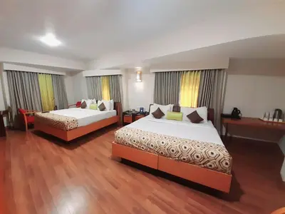 a hotel room with two beds and wooden floors at Meadows Residency in Ooty