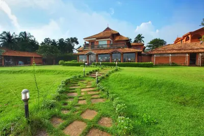 a house on a field with a path in front of it at The River Retreat Heritage Ayurvedic Resort in Shoranūr