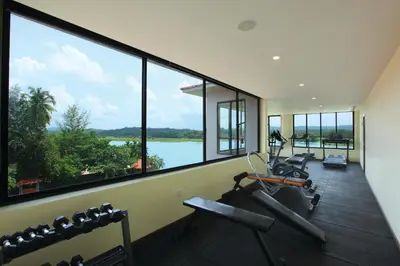 a gym with large windows with a view of the water at The River Retreat Heritage Ayurvedic Resort in Shoranūr