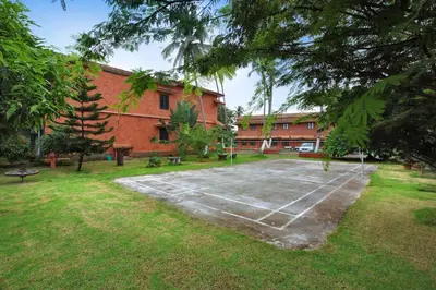 a tennis court in front of a building at The River Retreat Heritage Ayurvedic Resort in Shoranūr