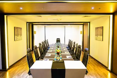 a conference room with a long table and chairs at Flora Airport Hotel and Convention Centre Kochi in Nedumbassery