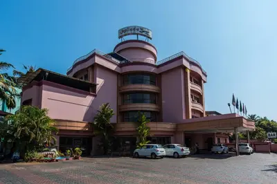 a pink building with cars parked in front of it at Kallada Regency in Irinjālakuda