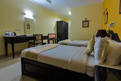 a hotel room with two beds and a sink at Kallada Regency in Irinjālakuda
