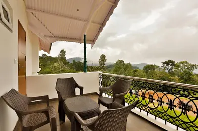 a balcony with chairs and a table and a view at Mystique stay resort in Kotagiri