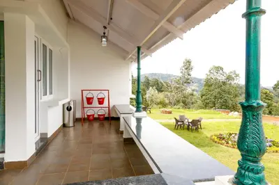a porch of a house with green columns at Mystique stay resort in Kotagiri