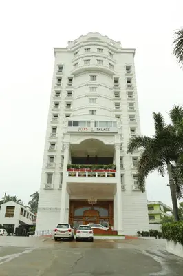 a white building with cars parked in front of it at Joys Palace Hotel in Trichūr
