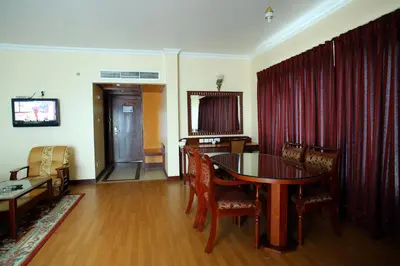 a living room with a dining room table and red curtains at Joys Palace Hotel in Trichūr